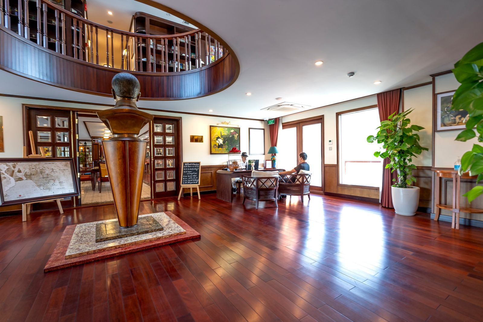 Elegant wood-paneled lounge interior with a central sculpture, the kind of space shown at a cruise ship interiors expo
