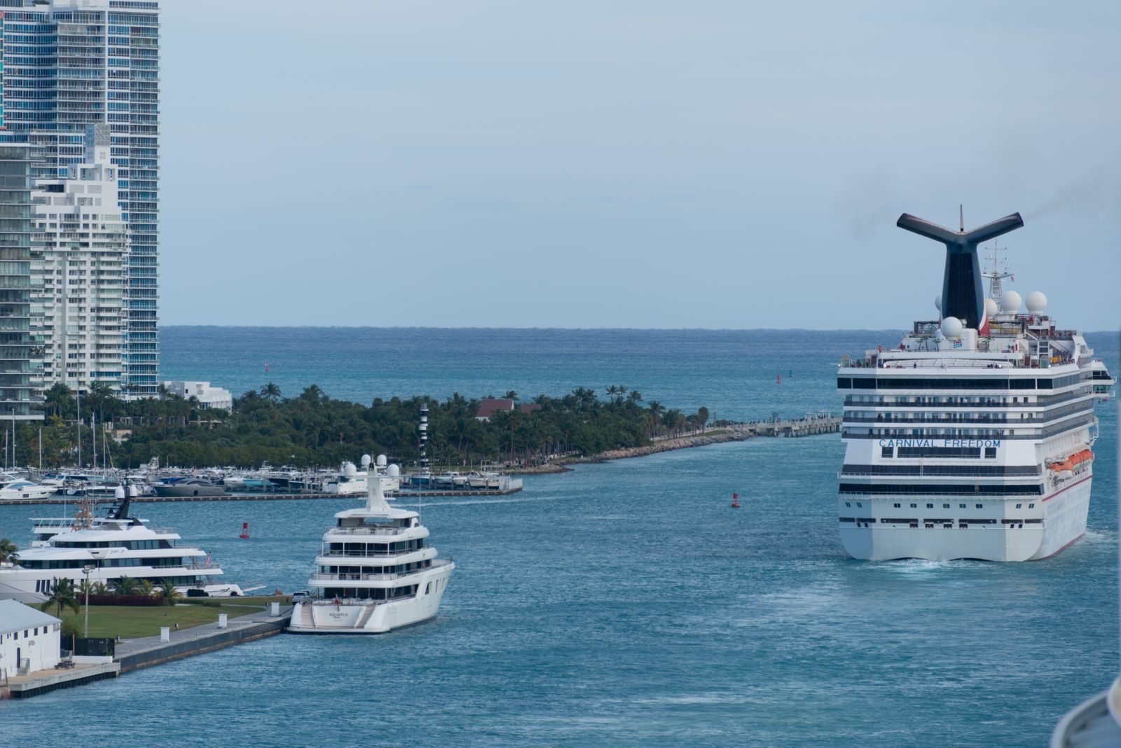 Cruise ship heading out to sea past moored yachts and waterfront towers