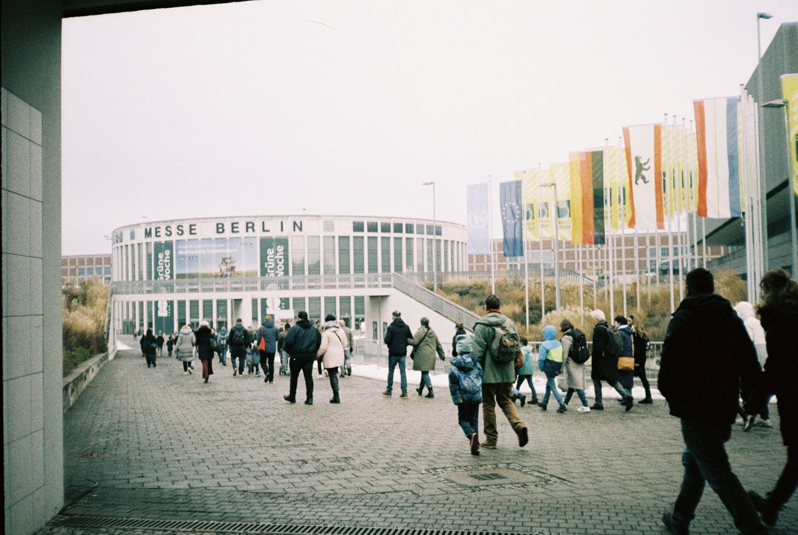 Visitors walking toward the Messe Berlin exhibition halls under rows of flags, the kind of venue that hosts an international cruise show