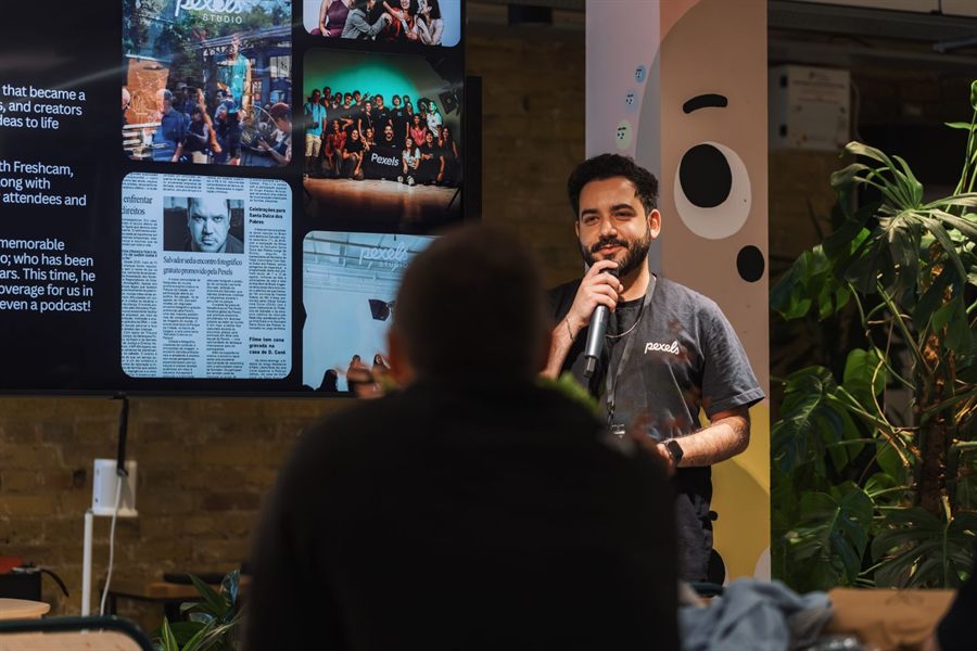 Speaker with a microphone presenting to an audience in front of a screen